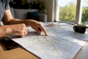 Unas manos señalan diferentes lugares en un mapa local sobre la mesa.