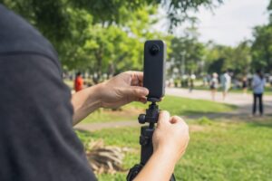 Manos ajustando una cámara 360 en un monopod al aire libre